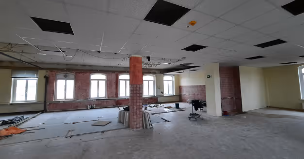 Altbausanierung: Gewerbehalle mit Backsteinwänden und abgehängter Rasterdecke während der Arbeiten