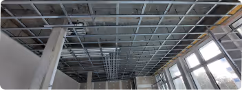 Abgehängte Decke im Bau: Metallunterkonstruktion vor großen Fenstern
