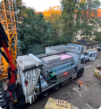 Anlieferung von Gipskartonplatten und Dämmstoff per Kran-Lkw auf der Baustelle