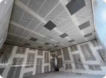 Akustikdecke mit Lochplatten während der Montage, Wände teils beplankt